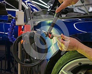 The mechanic at the auto shop with tools to repair dents in car body. Body repair.