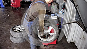 Mechanic balancing a car wheel on an automated machine checking