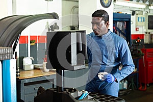 Mechanic balancing tire in auto repair shop using computer