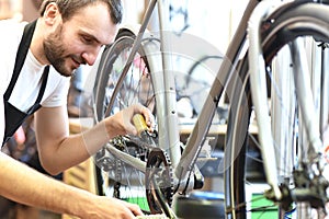 Mechanic in a bicycle repair shop oiling the chain of a bike