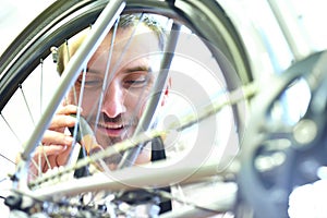 Mechanic in a bicycle repair shop oiling the chain of a bike