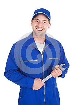 Mechanic in blue overalls holding spanner