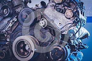 Mechanic in blue uniform lying down and working under car at auto service garage