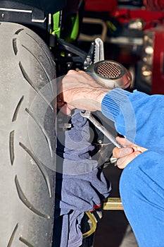 Mechanic carrying out a repair on the rear brake of a motorbike in the workshop