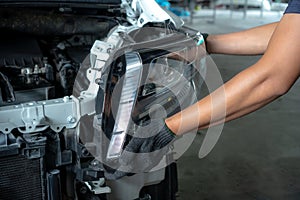 Mechanic changing car headlight in a workshop