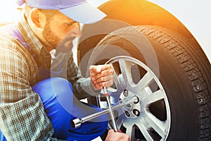 Mechanic changing car tire with wrench