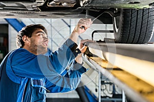 Mechanic Changing Tire From Suspended Car At Automobile Shop photo