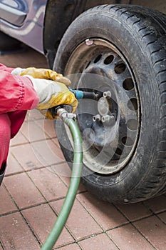 Mechanic changing wheel on car with pneumatic wrench