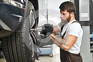 Mechanic changing wheel hubcap in automobile.