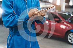 mechanic checking car maintenance list jobs and notes detail of repairs part in the auto service shop