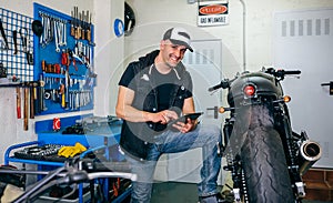 Mechanic checking custom motorcycle with tablet