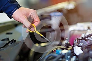 Mechanic checking engine oil in auto repair shop