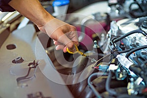 Mechanic checking engine oil in auto repair shop