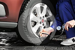 Mechanic checking tire air pressure at car service