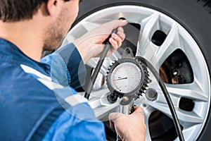 Mechanic Checking Tire Pressure With Gauge