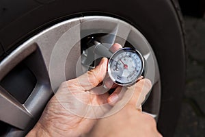 Mechanic checking tire pressure using gauge photo