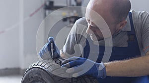 Mechanic checking tire tread depth and wear