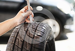 Mechanic checking Tire Tread Measurements with calipers tool