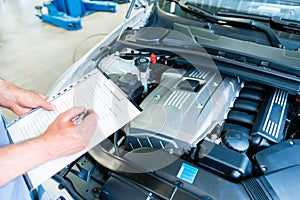 Mechanic with checklist in car workshop