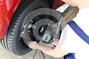 Mechanic checks air pressure from the car tyre in a garage