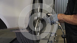 A mechanic checks the pressure in the wheels of a car at a service station.