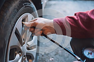 Mechanic checks tire pressure using pneumatic compressor with pressure gauge