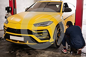 Mechanic checks tire pressure in yellow sport car suv