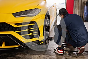 Mechanic checks tire pressure in yellow sport car suv