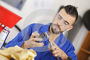 Mechanic cleaning auto part in workshop