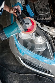 Mechanic cleaning headlights with polishing power buffer machine