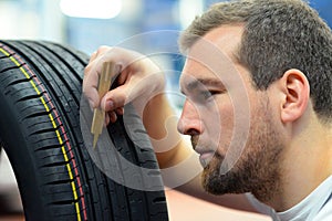 Mechanic controls tread depth of a car tyre