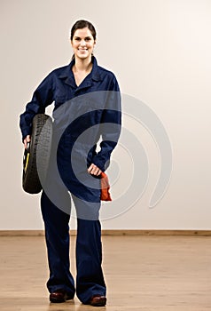 Mechanic in coveralls holding tire