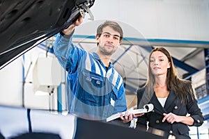 Mechanic and customer looking under the hood of a car