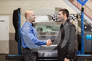 Mechanic and customer shaking hands at car service