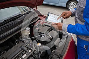 Mechanic With Digital Tablet While Examining Car