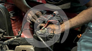 Mechanic with dirty hands uninstalling and fixing car engine details.