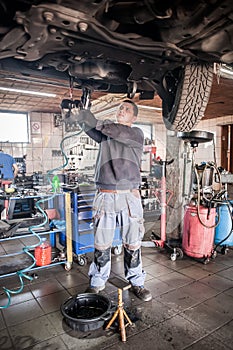 Mechanic discharges motor oil from engine tank under the car photo