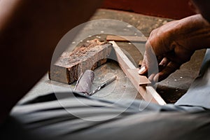 A mechanic does carpenter jobs with wood, plus and other tools. He is hitting hammer on the head of nail to wooden pieces and