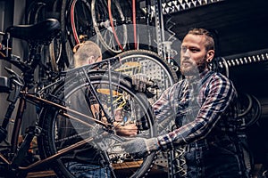 Mechanic doing bicycle wheel service manual in a workshop.
