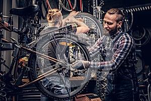 Mechanic doing bicycle wheel service manual in a workshop.