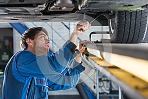 Mechanic examining the suspension of a car during a MOT Test photo