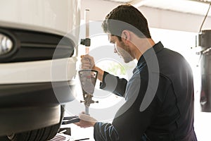 Mechanic Examining Tire Alignment With Camber Adapter