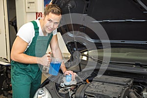 Mechanic fills coolant or cooling fluid in motor of a car