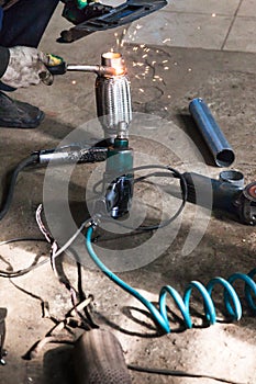 Mechanic fixes pipe on corrugation silencer photo