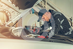 Mechanic fixing components under car hood