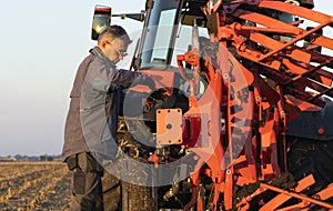 Mechanic fixing plow on the tractor