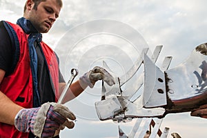 Mechanic fixing plow on the tractor