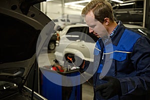 Mechanic in garage checking motor oil level at a car. Car engineer technician in the car repair shop. Automobile maintenance and