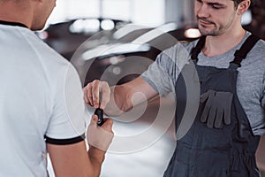 Mechanic gives keys to the owner of the repaired car in the workshop