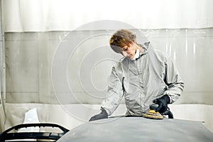 Mechanic grinds car part for painting. Car body work auto repair paint after accident